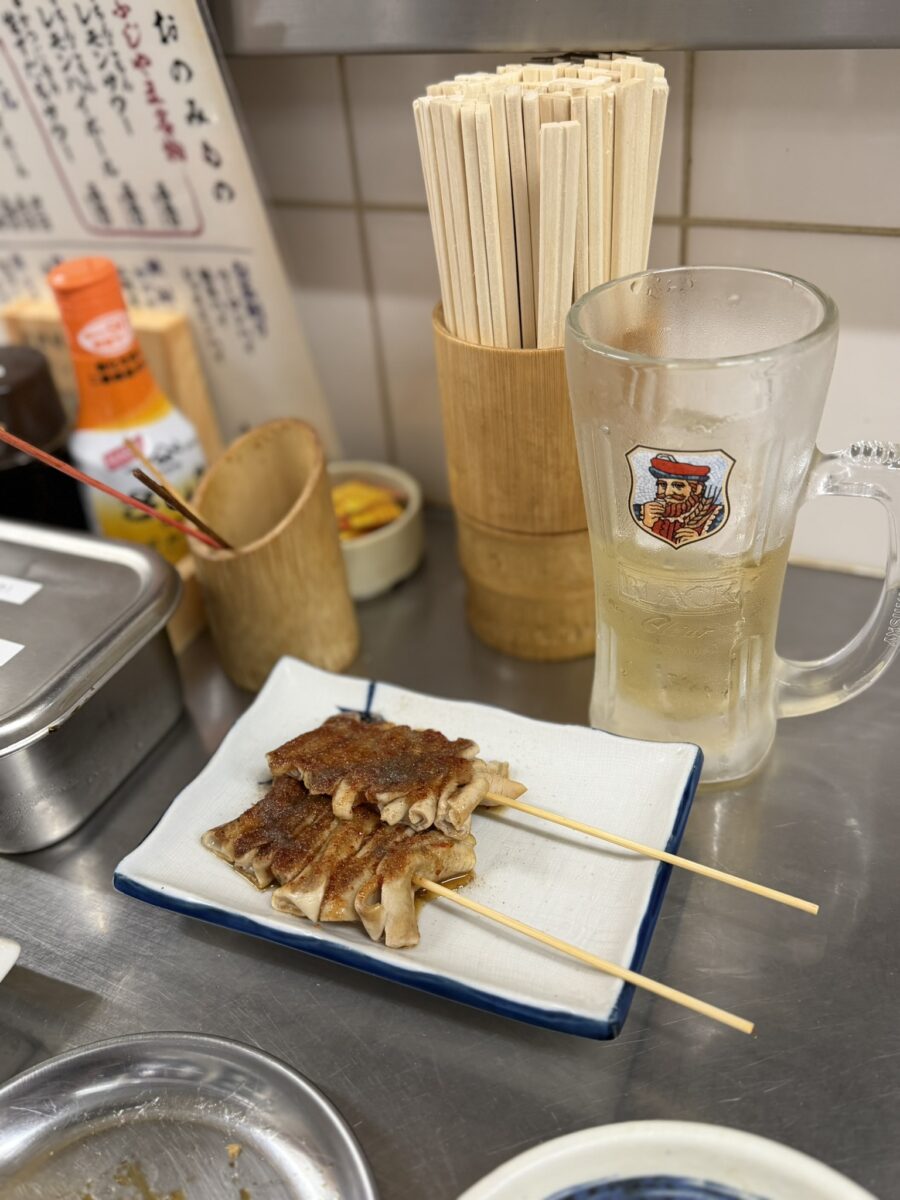 新世界の立ち飲み店のカウンター。串と生ビールが並ぶ
